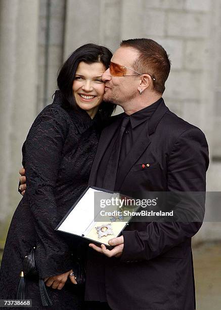 Bono, birth name Paul Hewson, poses with his wife Ali Hewson after receiving a Knighthood from Ambassador David Reddaway awarded to him by Her...