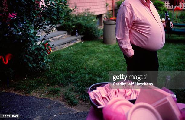 Decked out in pink a man swigs back on a beer at Jill Hunter's house at a party held in honor of the plastic pink flamingo on June 13, 2004 in West...