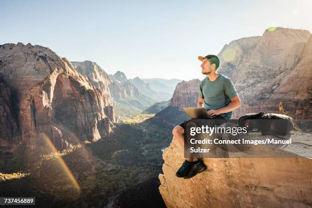 man hiking angels landing trail, sitting on rock, using laptop, zion national park, utah, usa - outdoor guy sitting on a rock stock pictures, royalty-free photos & images