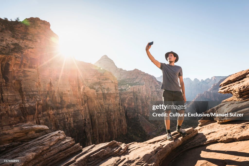 Man standing on rock, taking selfie, using smartphone, Zion National Park, Utah, USA