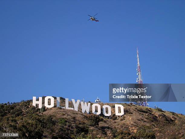 Fire department helicopter flies over the Hollywood sign, after filling up on water, to extinguish the brush fire that broke out in the Hollywood...