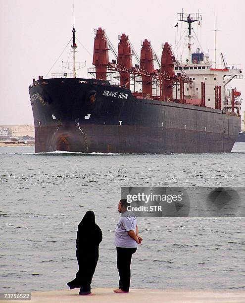 An Egyptian couple stands on a pier as a cargo ship cruises in the Suez Canal near the Egyptian city of Ismailia, 100 kms northeast of Cairo, 31...