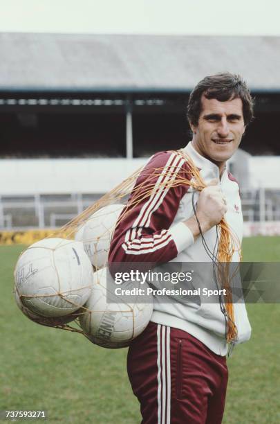 English professional footballer and goalkeeper with Tottenham Hotspur, Ray Clemence pictured standing on the pitch with a string bag of footballs at...