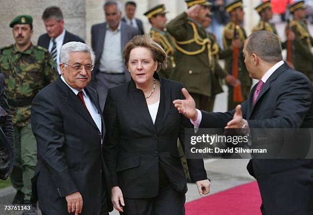 Palestinian official gestures to President Mahmoud Abbas and German Chancellor Angela Merkel during a welcoming ceremony for Merkel at Abbas's...