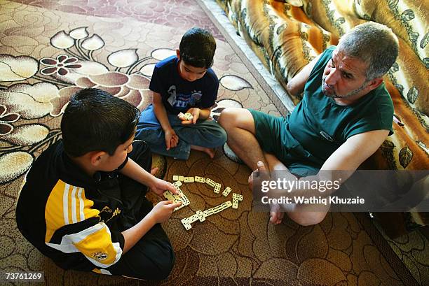 Fuad Mosa Muhammad, age 40, plays domino with his sons Ahmed and Muhammad at his house on March 28, 2007 in Baghdad, Iraq. Fuad, a cook at a...