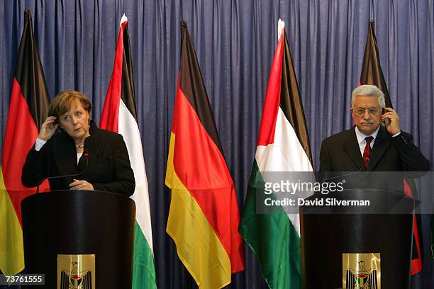 German Chancellor Angela Merkel and Palestinian President Mahmoud Abbas adjust their simultaneous translation earpieces during their joint press...