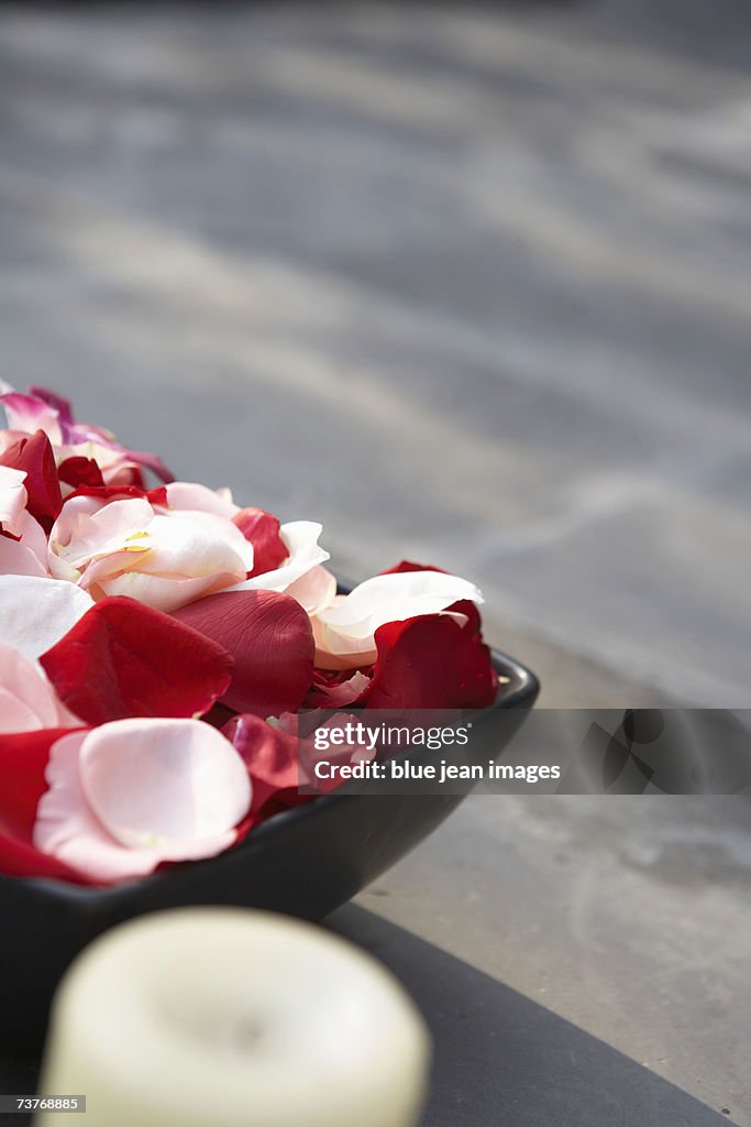 Close up of rose petals in bowl, with accompanying herbal candle.