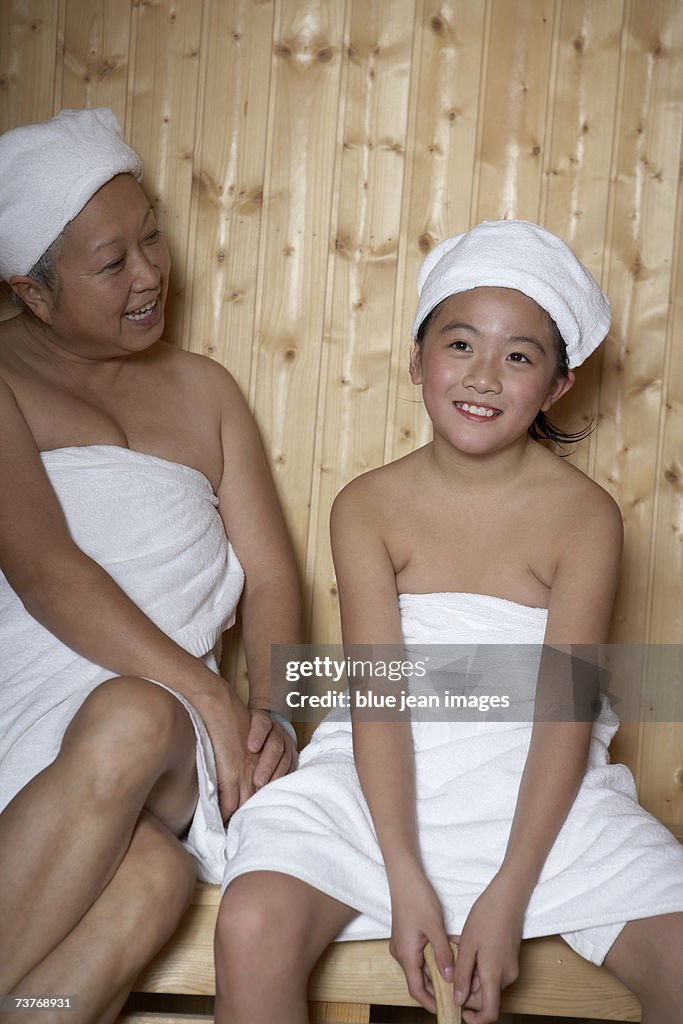 Grandmother And Granddaughter Wrapped In Towels Smile As They