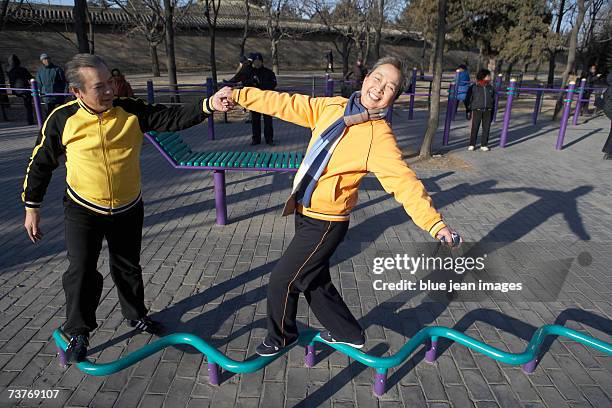 mature couple playfully walk on balance beam while enjoying a day at the park - playground balance beam stock pictures, royalty-free photos & images