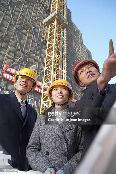man and woman smile and another man points up at construction project. - executive smile pointing bildbanksfoton och bilder