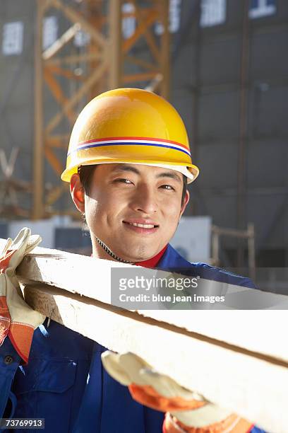 young man at construction site, carrying 2 x 4's, close up. - beton person close stock-fotos und bilder