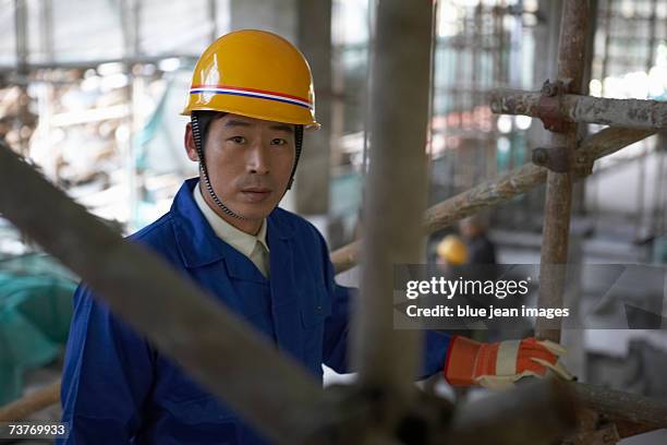 middle age man at construction site, scaffold in foreground, close up, portrait. - beton person close stock-fotos und bilder