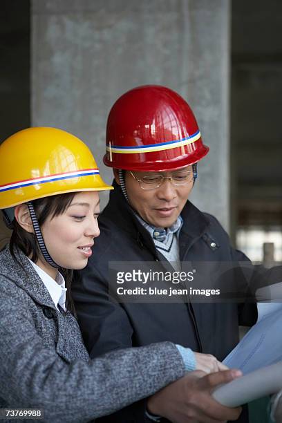 middle age man showing blueprints to woman, woman pointing at blueprints, close up. - beton person close stock-fotos und bilder