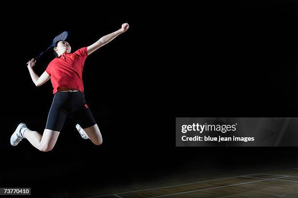 young woman leaps high in the air and prepares to smash a shuttlecock during a game of badminton. - badminton smash stock pictures, royalty-free photos & images