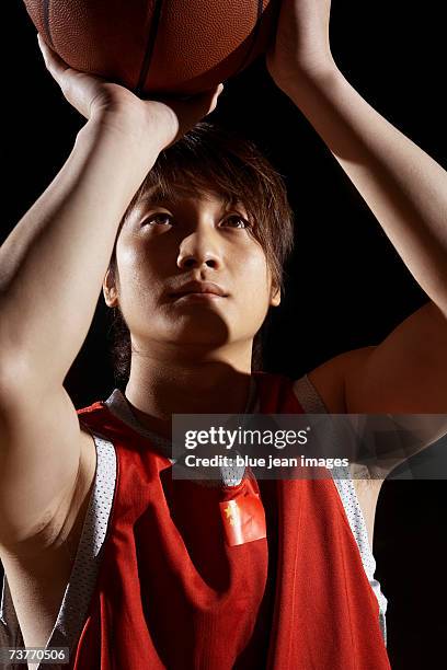 close-up of a young man preparing to shoot a basketball in a darkened gymnasium. - basketball close up ストックフォトと画像