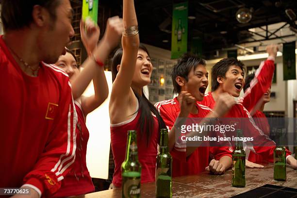 a group of sports fans in matching clothing celebrate a victory at a sports bar - beer bottle mouth stock-fotos und bilder