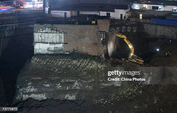 An excavator starts to demolish a building sitting on its own island of land amid construction all around it on April 2, 2007 in Chongqing...