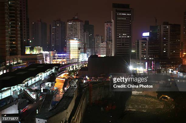An excavator starts to demolish a building sitting on its own island of land amid construction all around it on April 2, 2007 in Chongqing...
