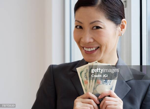 middle-aged asian businesswoman holding yen banknotes - tentação - fotografias e filmes do acervo