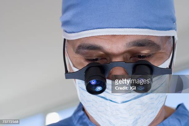 close up of african male doctor with surgical mask and binocular loupes - surgical loupes stock pictures, royalty-free photos & images