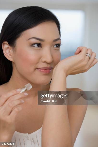 asian woman smelling perfume on wrist - wrist stock pictures, royalty-free photos & images