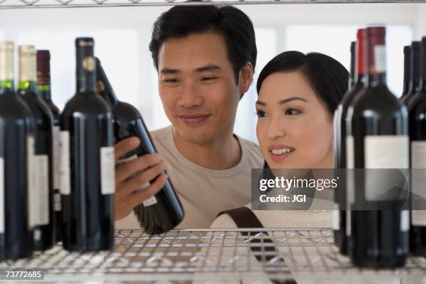 asian couple selecting wine - buying alcohol stock pictures, royalty-free photos & images