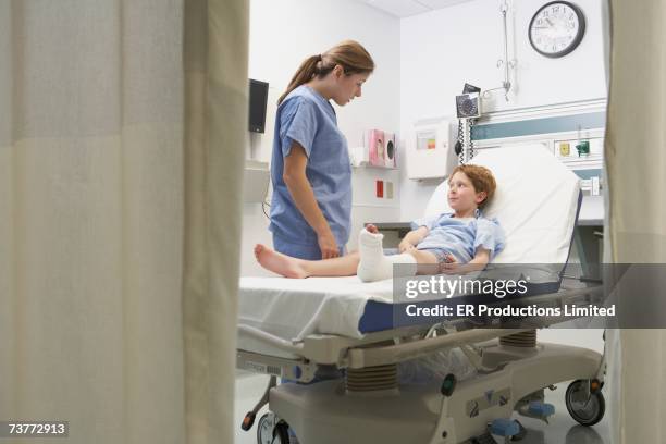 nurse talking to boy with broken leg in hospital bed - full body cast in bed stockfoto's en -beelden