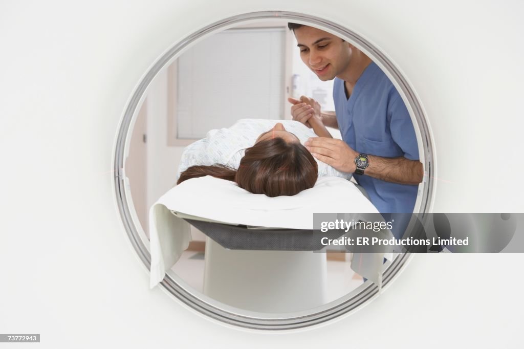 Indian nurse comforting patient entering MRI scanner