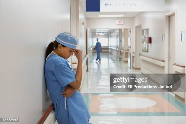 indian female doctor leaning against wall with head in hand - 9 to 5 stock pictures, royalty-free photos & images