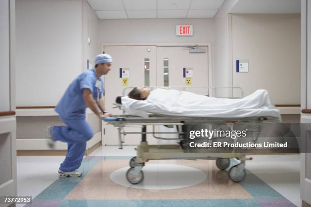 blurred motion shot of nurse wheeling gurney in hospital - operatiegewaad stockfoto's en -beelden