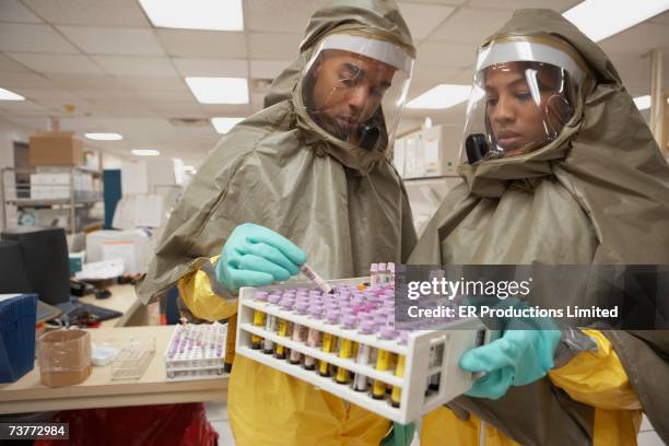 african scientists in hazmat suits looking at tray of vials - 防護服 個照片及圖片檔