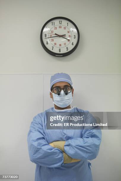 male surgeon standing under wall clock - surgical loupes stock pictures, royalty-free photos & images