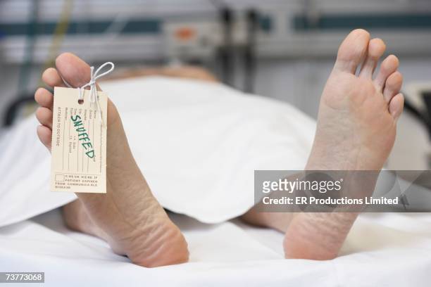 close up of dead man's feet with toe tag reading snuffed - funeral parlor ストックフォトと画像