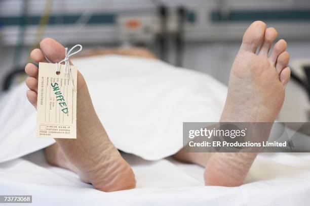 close up of dead man's feet with toe tag reading snuffed - funeral parlor stockfoto's en -beelden