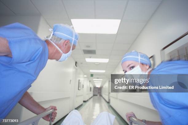 male and female doctors wheeling gurney down corridor - bår på hjul bildbanksfoton och bilder