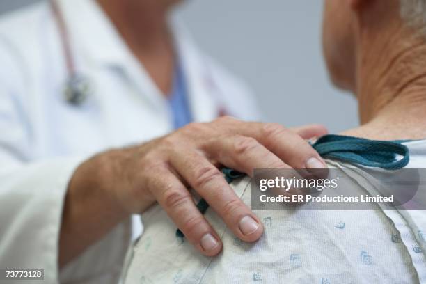 close up of doctor's hand on senior patient's shoulder - hand on shoulder stock pictures, royalty-free photos & images