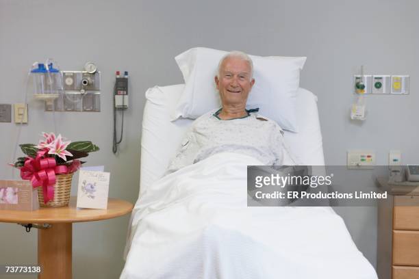 senior male patient smiling in hospital bed - adult male hospital bed stock-fotos und bilder