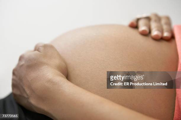 close up of pregnant african woman's hands on bare belly - beautiful bare women fotografías e imágenes de stock