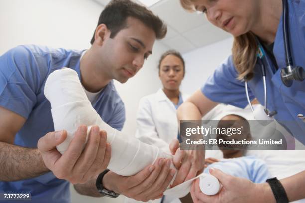 doctors wrapping african boy's leg in hospital - gebrochenes bein stock-fotos und bilder