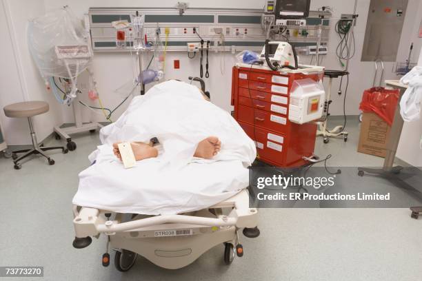 deceased patient under sheet with toe tag in emergency room - dead person stock pictures, royalty-free photos & images