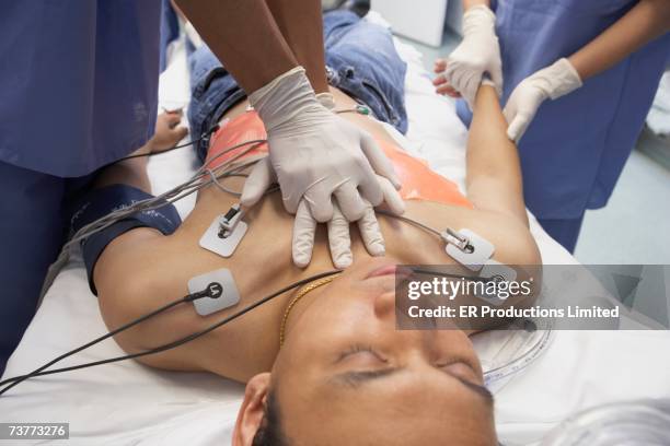 doctor performing cpr on asian patient in the emergency room - heart attack stockfoto's en -beelden