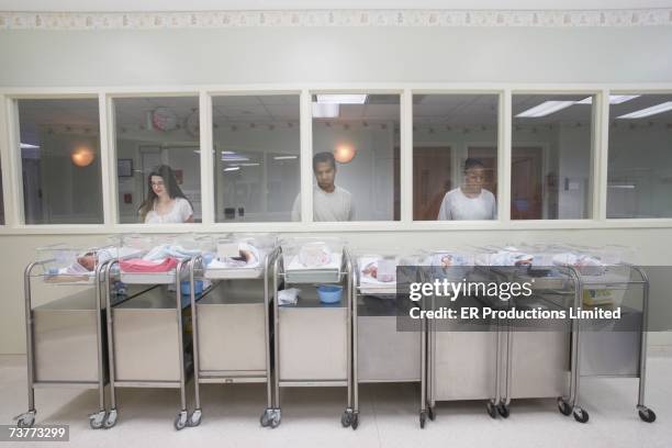 new parents watching babies in hospital nursery - lettino ospedale foto e immagini stock