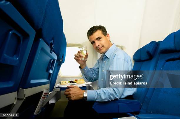 man eating and toasting with wine on airplane - airline food stock-fotos und bilder
