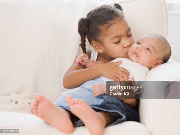 african girl kissing baby sibling - siblings baby stock pictures, royalty-free photos & images