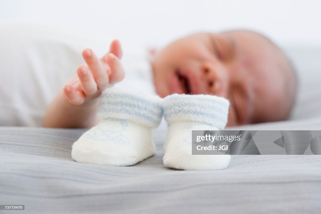 Close up of baby booties next to sleeping newborn baby