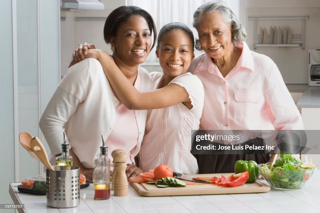 Three generations of African women preparing food in kitchen