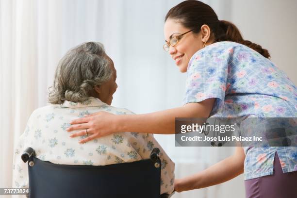 female nurse helping senior african woman in wheelchair - honduras people stock pictures, royalty-free photos & images