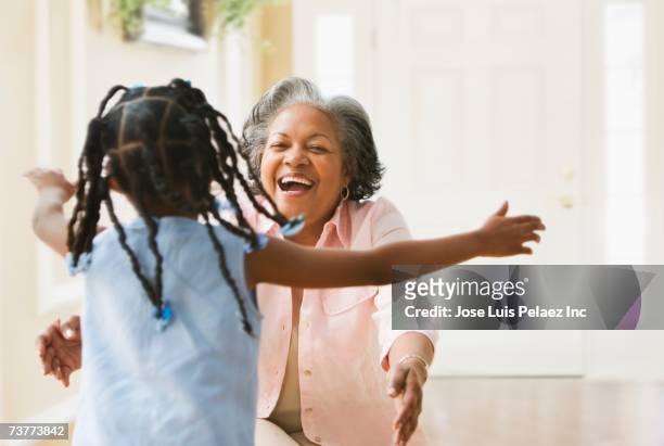 african grandmother and granddaughter running to hug each other - granddaughter stock pictures, royalty-free photos & images