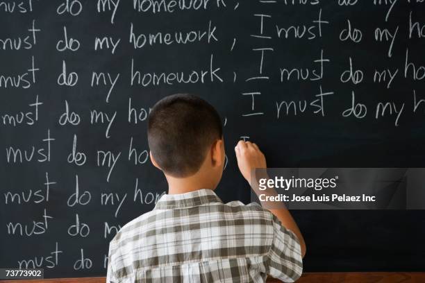 rear view of boy writing on blackboard - child writing on chalkboard stock pictures, royalty-free photos & images