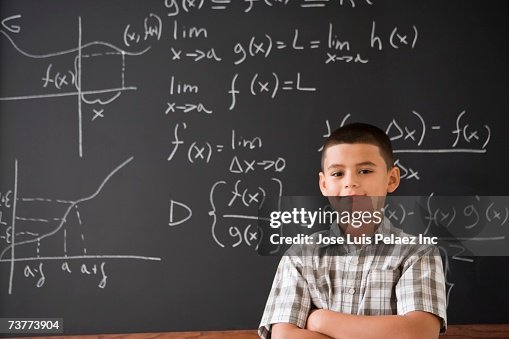 Hispanic boy smiling in front of math formula on blackboard Hispanic boy smiling in front of math formula on blackboard